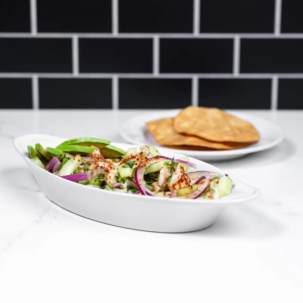 Mexican shrimp ceviche with avocado, red onion, and cucumber, served with tostadas.
