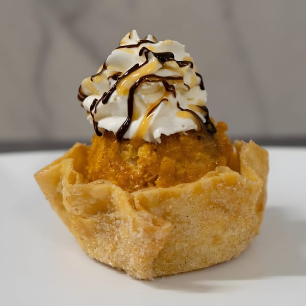 Mexican fried ice cream dessert in a crispy shell, topped with whipped cream, chocolate, and caramel.